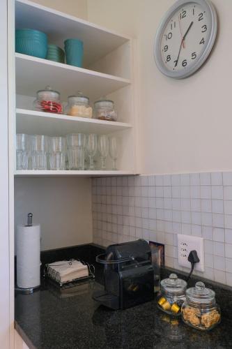 a kitchen counter with a clock on the wall at High Season Farm Luxury Cottages in Hermanus