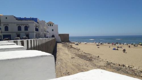 a beach with people and buildings and the ocean at Grande demeure de charme in Asilah