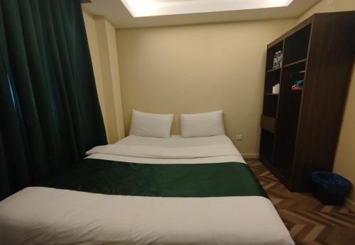 a small bedroom with a bed with a green and white sheets at Fast Hotel Setapak Near Tunku Abdul Rahman UMT KL in Kuala Lumpur