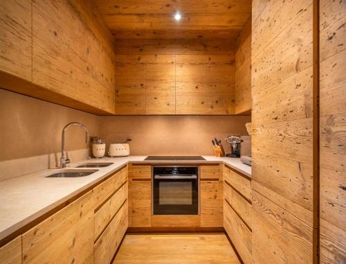 a kitchen with wooden cabinets and a sink and a stove at Tablà del Bosco R&R in Cortina dʼAmpezzo