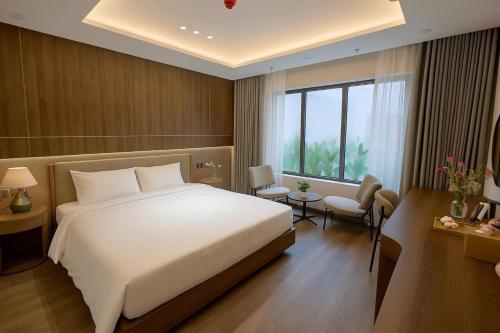 a bedroom with a large white bed and a window at Nature Hotel - Lac Long Quan in Hanoi