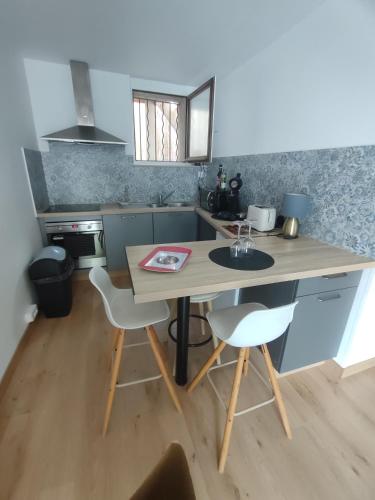 a kitchen with a wooden table and two chairs at appartement dans maison de village in Pinet