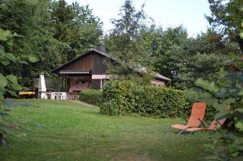 a chair sitting in the grass in front of a house at Haus Waldfrieden OG in Thalfang