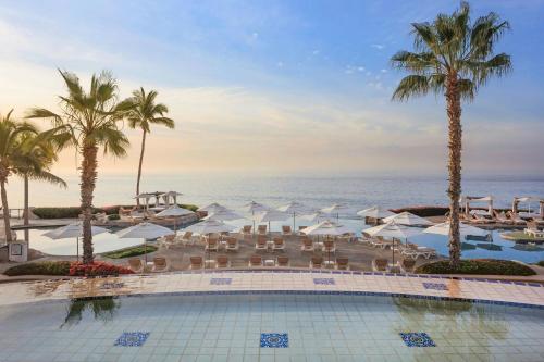 a pool with chairs and umbrellas and the ocean at Hacienda del Mar Los Cabos, an Autograph Collection All-Inclusive Resort in Cabo San Lucas