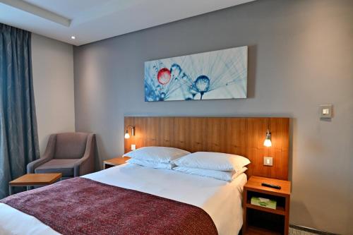 a hotel room with a bed and a chair at City Lodge Hotel Waterfall City in Midrand