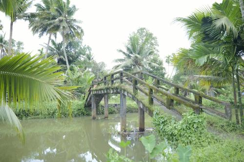 a wooden bridge in the middle of a pond at Ra Ga Riverside - 2 Bedroom Retreat in Kumarakom