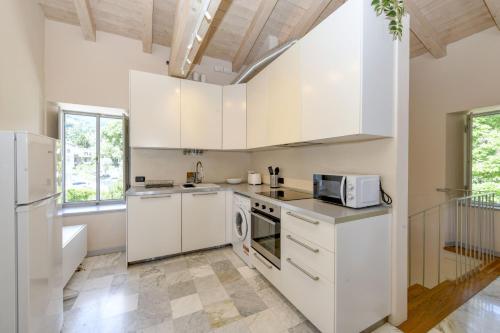 a kitchen with white cabinets and a microwave at La Darsena by Garda FeWo in Montecucco