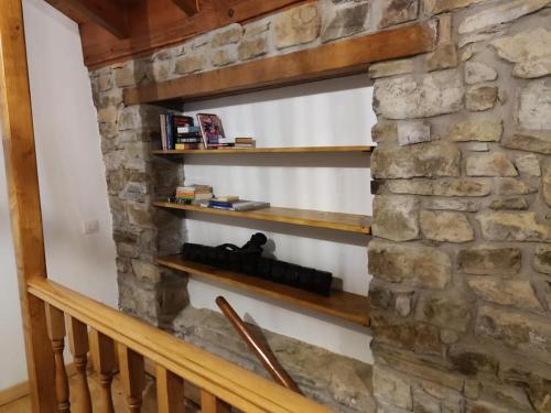 a stone wall with wooden shelves in a room at La Casuca de la Brevera in Pesaguero-La Parte