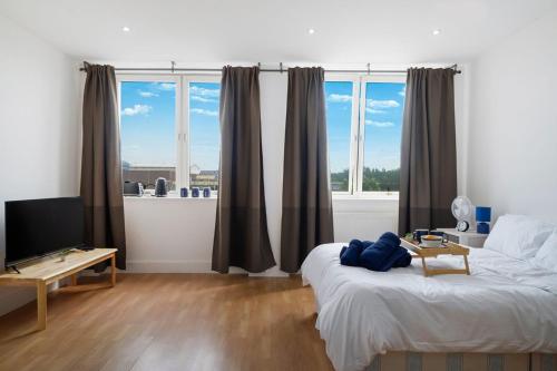 a bedroom with a bed and a tv and windows at Lovely Private Large Studio with Parking in Borehamwood
