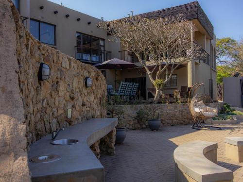 a stone wall with a bench in front of a building at 8 On Penny Guesthouse in Nelspruit