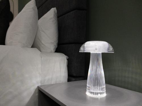 a silver lamp sitting on a table next to a bed at 8 On Penny Guesthouse in Nelspruit
