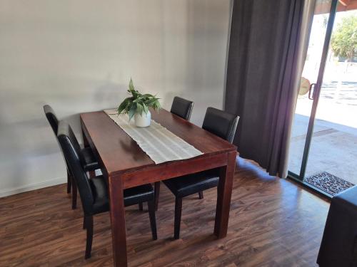 a dining room table with chairs and a potted plant on it at Heritage Caravan Park - Pet Friendly in Alice Springs