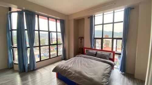 a bedroom with a bed and two large windows at Verve Nepal's Hostel in Kathmandu
