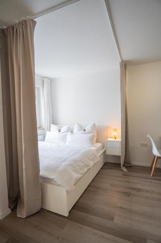 a white bedroom with a white bed and a window at Auenblick -Natur genießen, Leipzig erleben in Leipzig