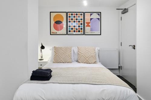 a bedroom with a bed with two paintings on the wall at Luxury Lower-Level Two Bed Apt in Headingley