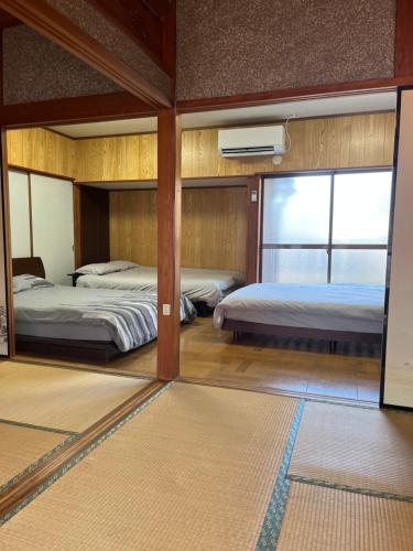 a bedroom with two beds and a mirror at なぎさの宿 日本文化古き良き建物畳敷 大家族グループ利用 長期滞在ok駐車場無料 日本の真ん中Mie Suzuka Ise in Tsu