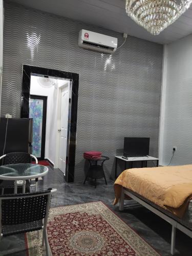 a bedroom with a bed and a table and a fan at Makwan Homestay C in Kubang Semang