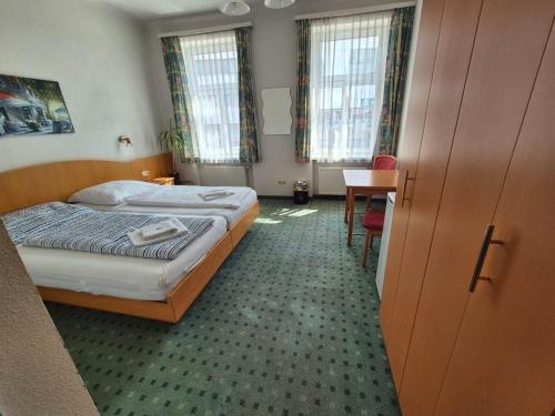 a bedroom with a bed and a desk and windows at Mariazellerhof Room 018 in Sankt Pölten