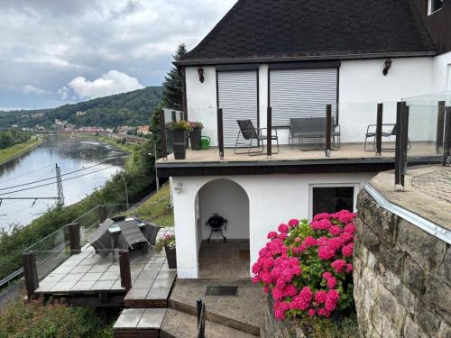 ein weißes Haus mit einem Balkon mit rosa Blumen in der Unterkunft Elbblick große Loftwohnung in Königstein an der Elbe
