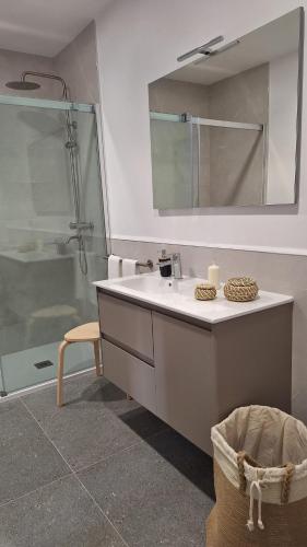 a bathroom with a sink and a shower with a mirror at Os Faros Pisos Turísticos in Arou