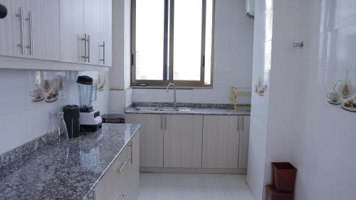 a white kitchen with a sink and a window at My Dream Apartment in Addis Ababa