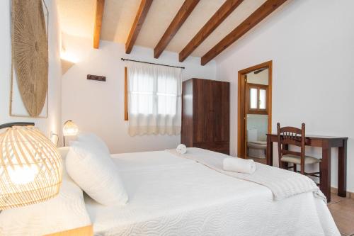 a bedroom with a large white bed and a table at Finca Peris in Caʼs Concos