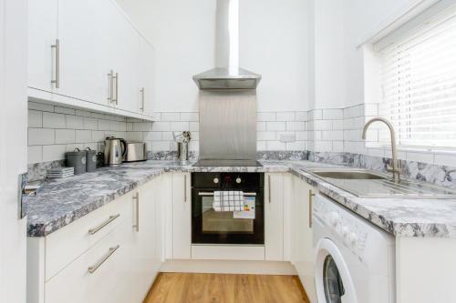 a kitchen with a stove and a sink at A modern cosy 2 bed Gateshead Newcastle house in Gateshead