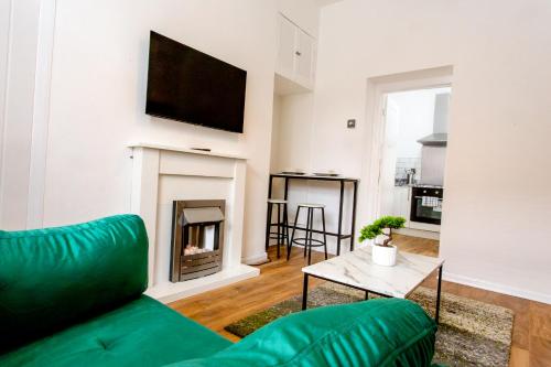 a living room with a green couch and a fireplace at A modern cosy 2 bed Gateshead Newcastle house in Gateshead