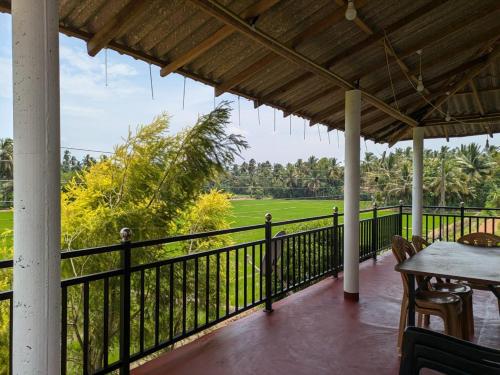 a porch with a table and a view of a field at Bird Nest Guest House in Lukasgoda