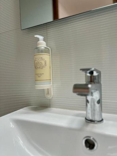 a bottle of soap sitting on a bathroom sink at Private Room in Old Town in Viana do Castelo