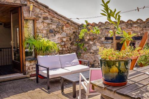 a patio with a couch and a potted plant at Les deux arches in Caunes-Minervois