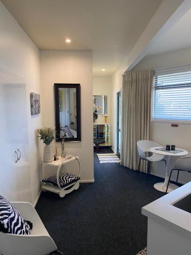 a living room with a mirror and a table at Maison Blue - Chic Garden Apartment - Pet Friendly in Napier