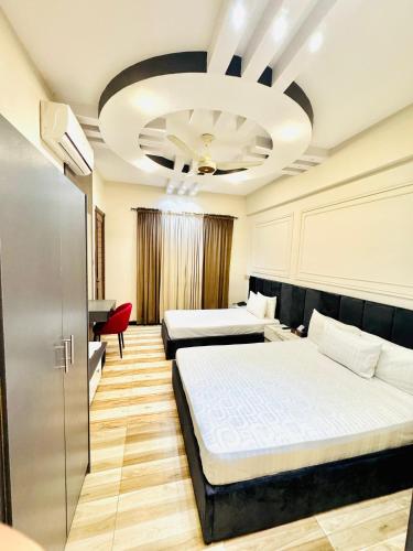 a hotel room with two beds and a red chair at Holiday One Hotel & Suites in Karachi