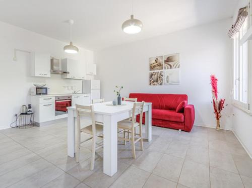 a living room with a white table and a red couch at Nour Apartments - Castramajora Alloggi in Casalmaggiore