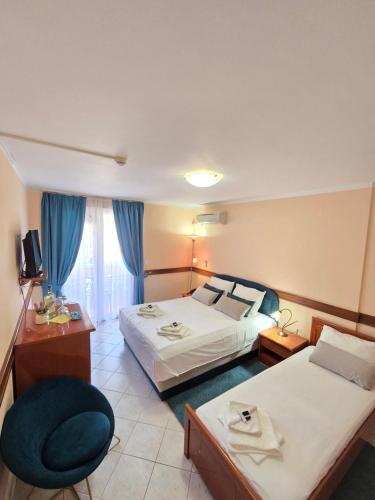 a hotel room with two beds and a chair at Garni Hotel Koral in Budva