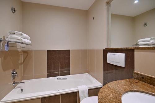 a bathroom with a tub and a sink at City Lodge Hotel Gqeberha in Port Elizabeth
