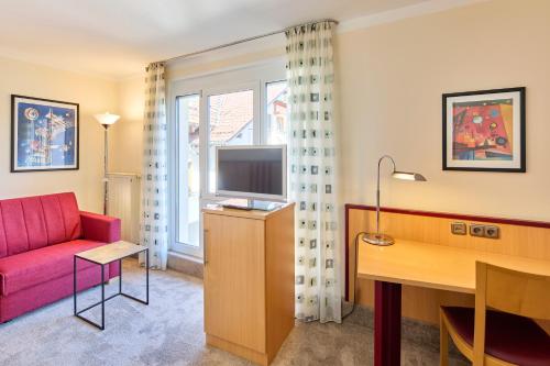 a living room with a red couch and a desk at Apartments Aschheim in Aschheim