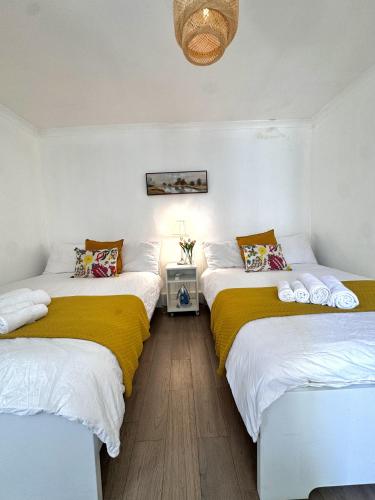 a room with two beds with yellow and white sheets at Stylish Entire Apartment with Private Garden in Camden, Central London in London