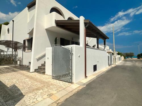 a white building with a gate on a street at Casa Paola vista mare - Starlink in Specchiolla 