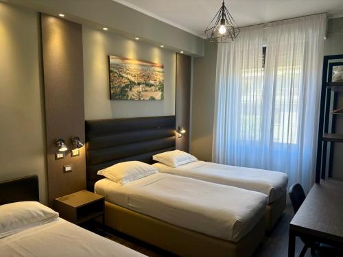 a hotel room with two beds and a chandelier at Hotel Perugino in Milan