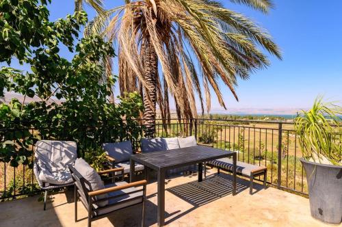 a table and chairs on a balcony with a palm tree at לה כינרה - ווילה מדהימה עם בריכה פרטית ונוף לכנרת במגדל in Migdal