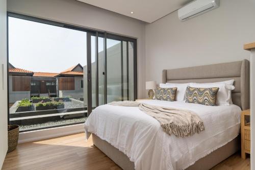 a bedroom with a large bed and a large window at Zimbali Luxury Garden Villa in Ballito