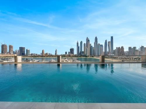 a swimming pool with a city skyline in the background at Designer Large 1 BR with Private Beach Infinity pool in Dubai Harbour in Dubai