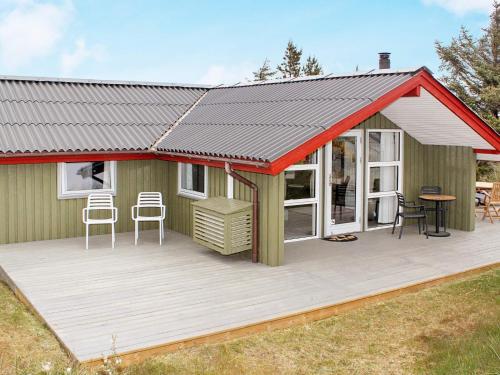 a green cabin with a deck with two chairs at Modern Cottage by Dunes - By Traum Ferienwohnungen in Vejers Strand