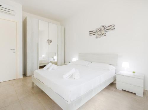 a white bedroom with a white bed and a mirror at Nour Apartments - Castramajora Alloggi in Casalmaggiore