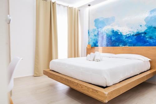 a bedroom with a white bed with a painting on the wall at La Terrazza sul Mare in Praia a Mare
