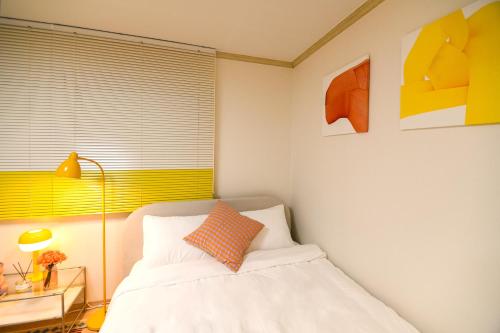 a bedroom with a white bed with a orange pillow at stay DAHOM in Seoul
