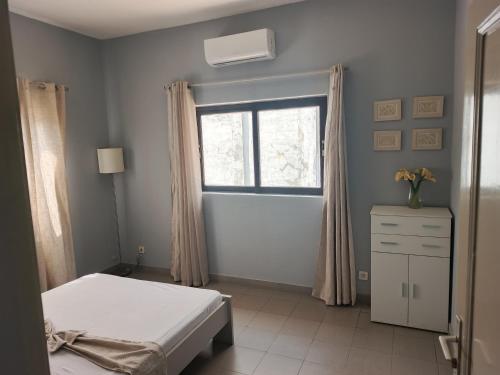 ein Schlafzimmer mit einem Bett, einem Fenster und einer Kommode in der Unterkunft B&B DEGNON Appart in Cotonou