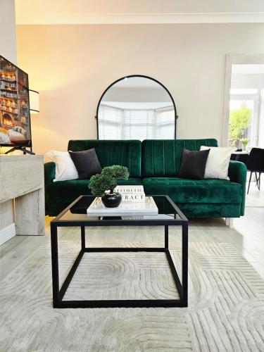 a living room with a green couch and a table at Long Short Stays Driveway 2-Bed Hull in Hull