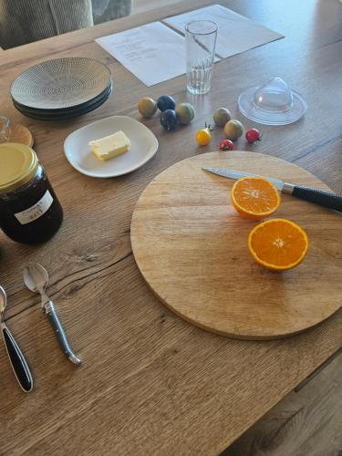a wooden table with a cutting board with fruit on it at Chambres d'hôtes chez Mylène et Guillaume in Denezé-sous-Doué